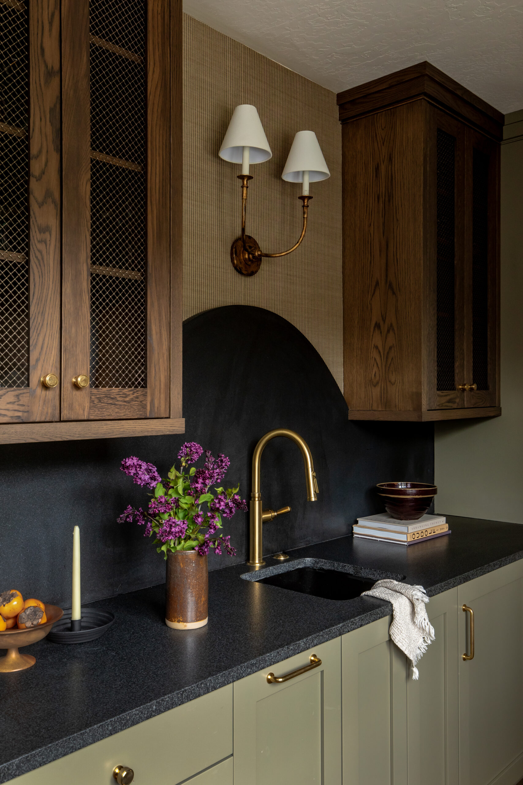 Custom bar area with dark wood cabinetry, brass fixtures, and black stone countertops in a luxury Utah home