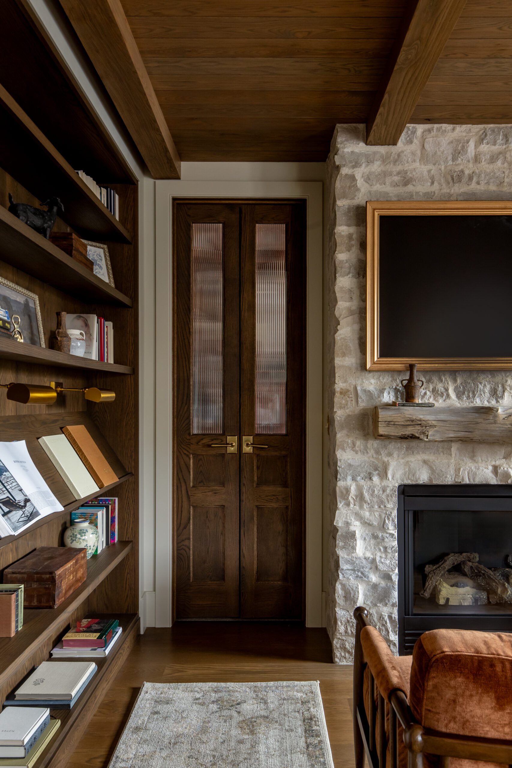 Custom home office with white stone fireplace, built-in wood shelving, and exposed beam ceiling in a luxury Utah home