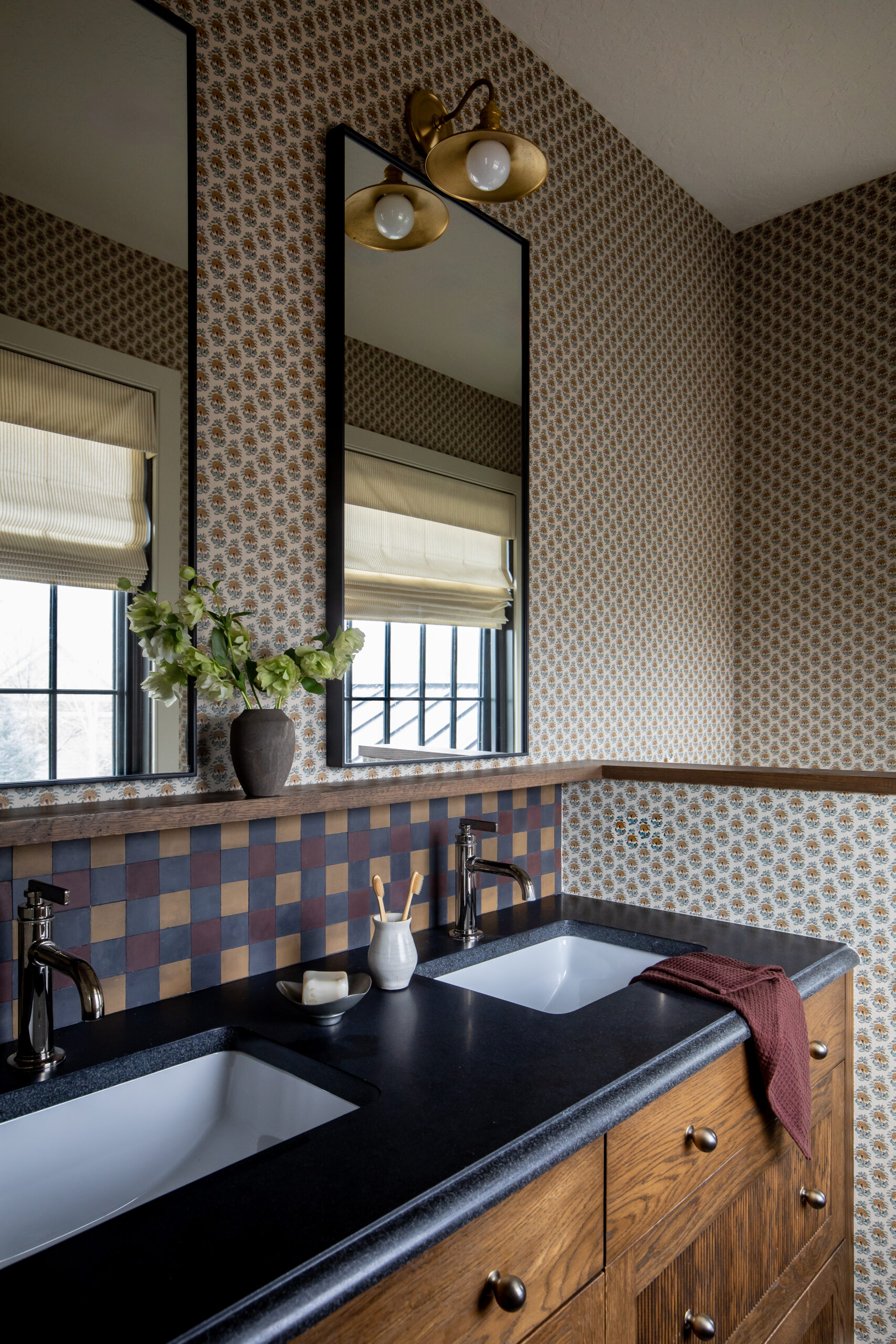 Custom double vanity with patterned wallpaper, wood cabinetry, and designer tile backsplash in a luxury Utah home